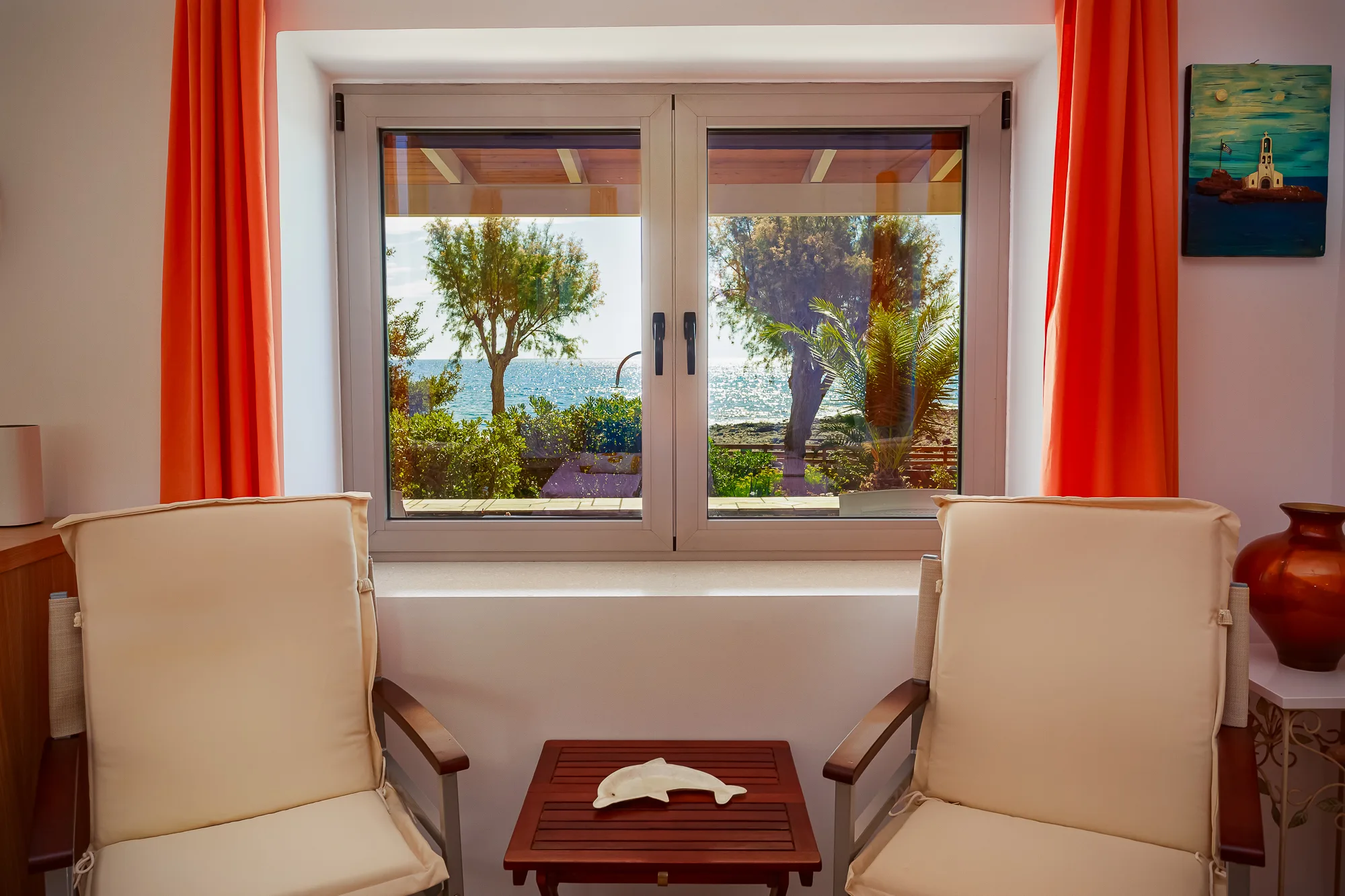 Villa Venus – sitting area with sea view window and orange curtains